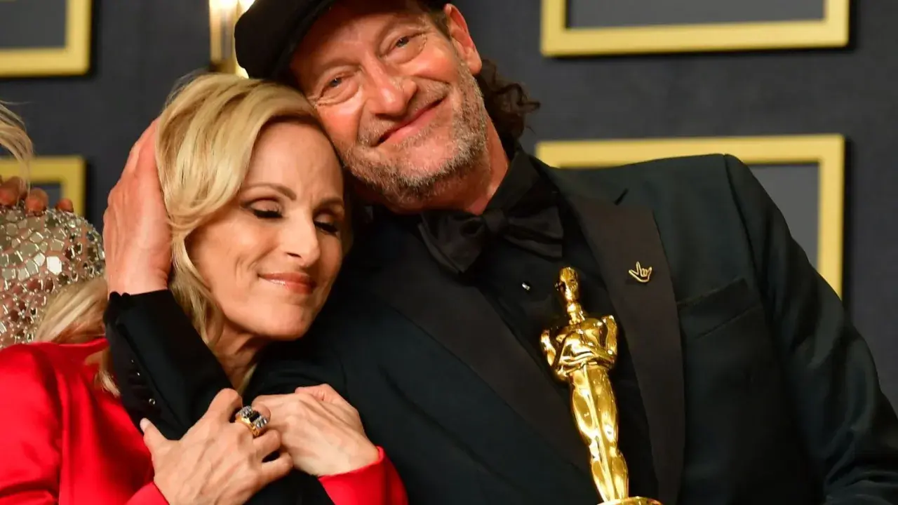 Il cast di coda, con i segni del cuore, celebra un momento d'oro. L'Oscar brilla, simbolo di un amore che supera ogni barriera.
