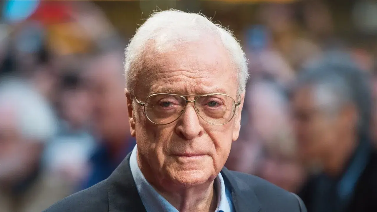 Michael Caine, icona del cinema, con occhiali e sguardo intenso. Un volto che ha segnato tanti film indimenticabili.