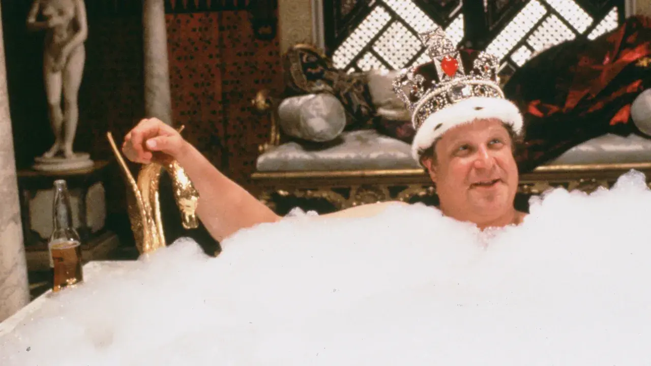 Un uomo con una corona scintillante, immerso in una vasca piena di schiuma, sorride. Sembra che sua maestà viene da Las Vegas, pronto per un bagno regale.