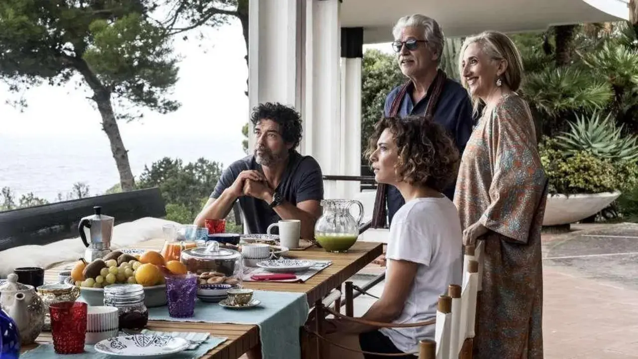 Una famiglia riunita per una colazione all'aperto, tra risate e sguardi pensierosi. Un momento di gioia e riflessione, una vera croce e delizia.