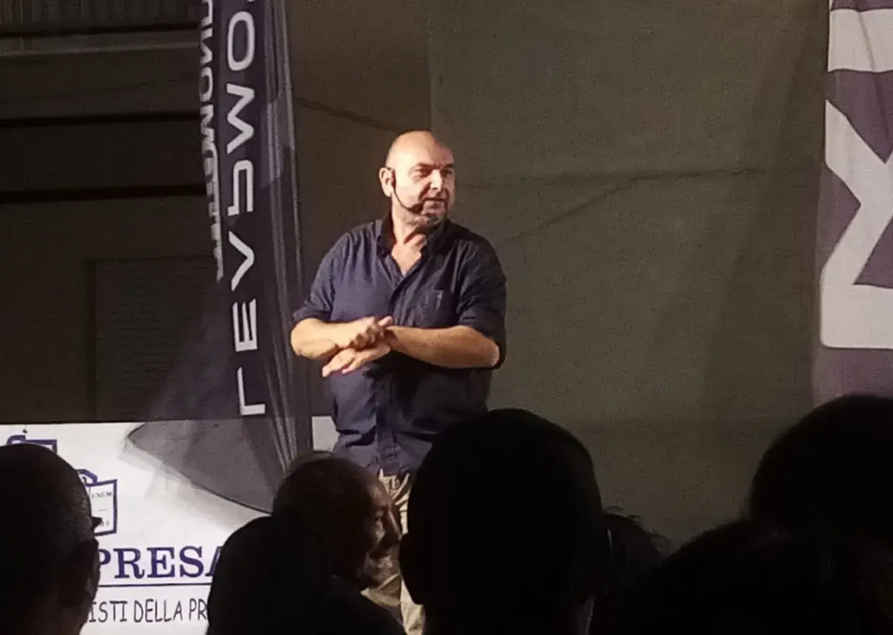 Giovanni Cacioppo, con un microfono all'orecchio, parla a un pubblico. La sua storia sulla malattia ispira.