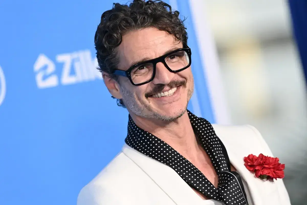 Pedro Pascal sorride con occhiali neri e un fiore rosso sul bavero. La sua vita privata è un mistero affascinante.