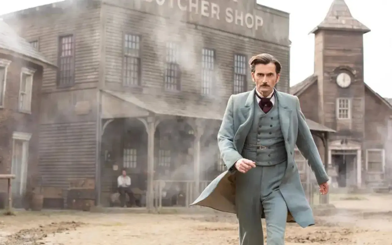 Phileas Fogg, protagonista de "il giro del mondo in 80 giorni serie tv", cammina in un villaggio polveroso.