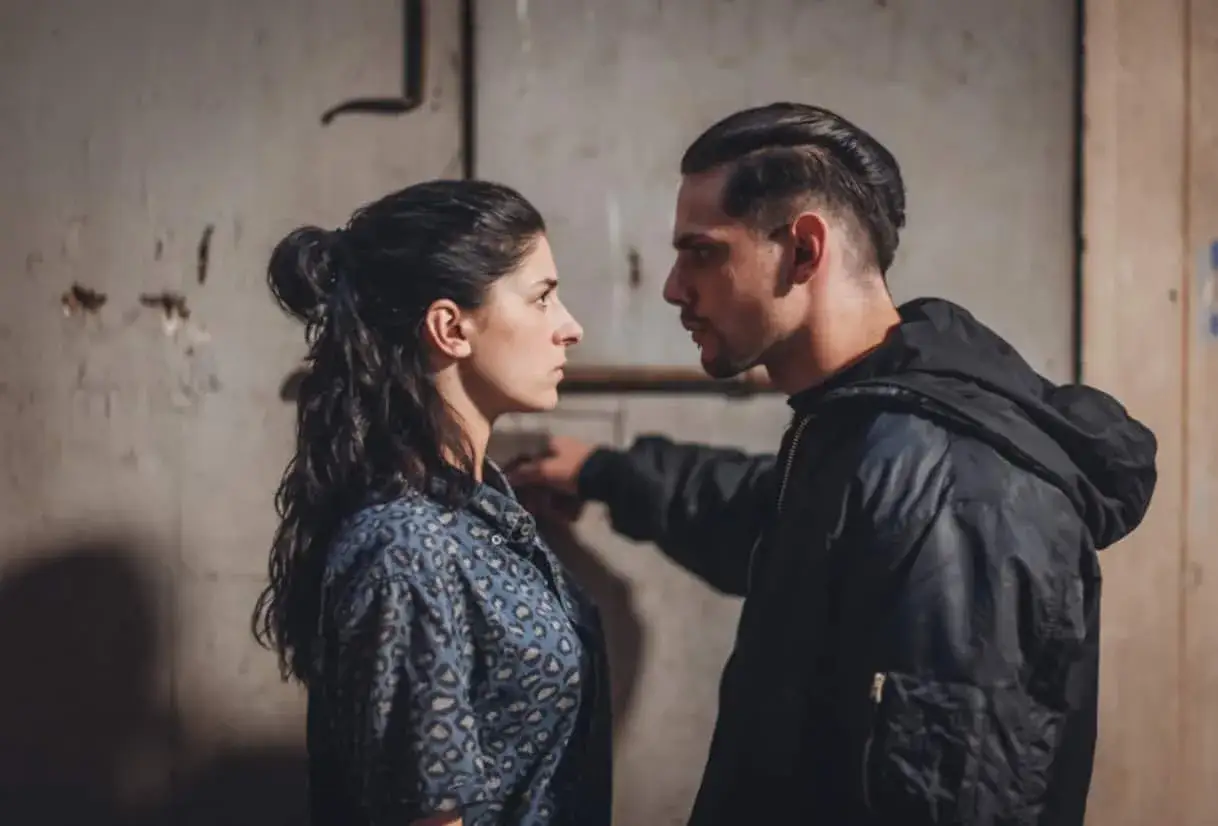 Una donna e un uomo si guardano intensamente, in un'atmosfera tesa che ricorda la serie