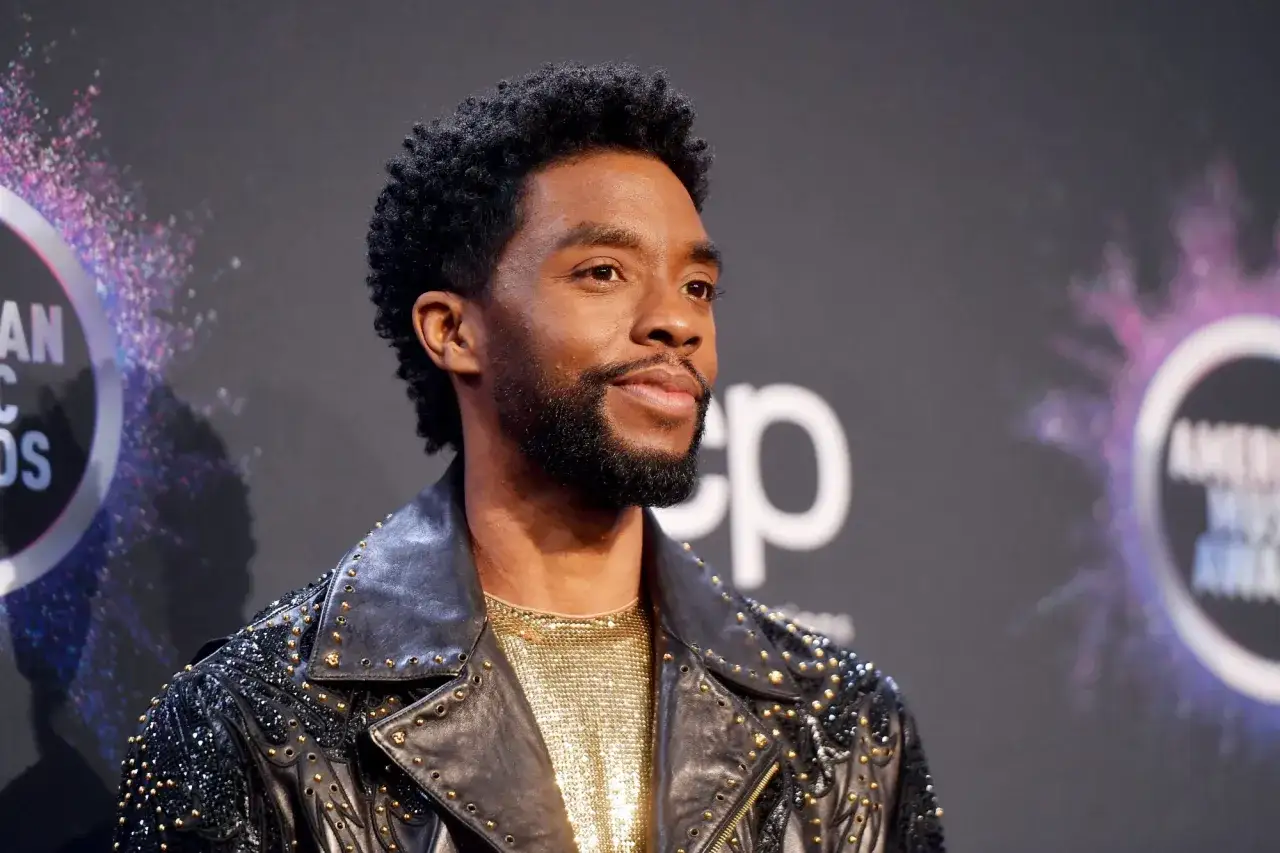 Chadwick Boseman, icona di stile, prima della sua tragica morte. Indossa una giacca di pelle borchiata e una maglia dorata scintillante.