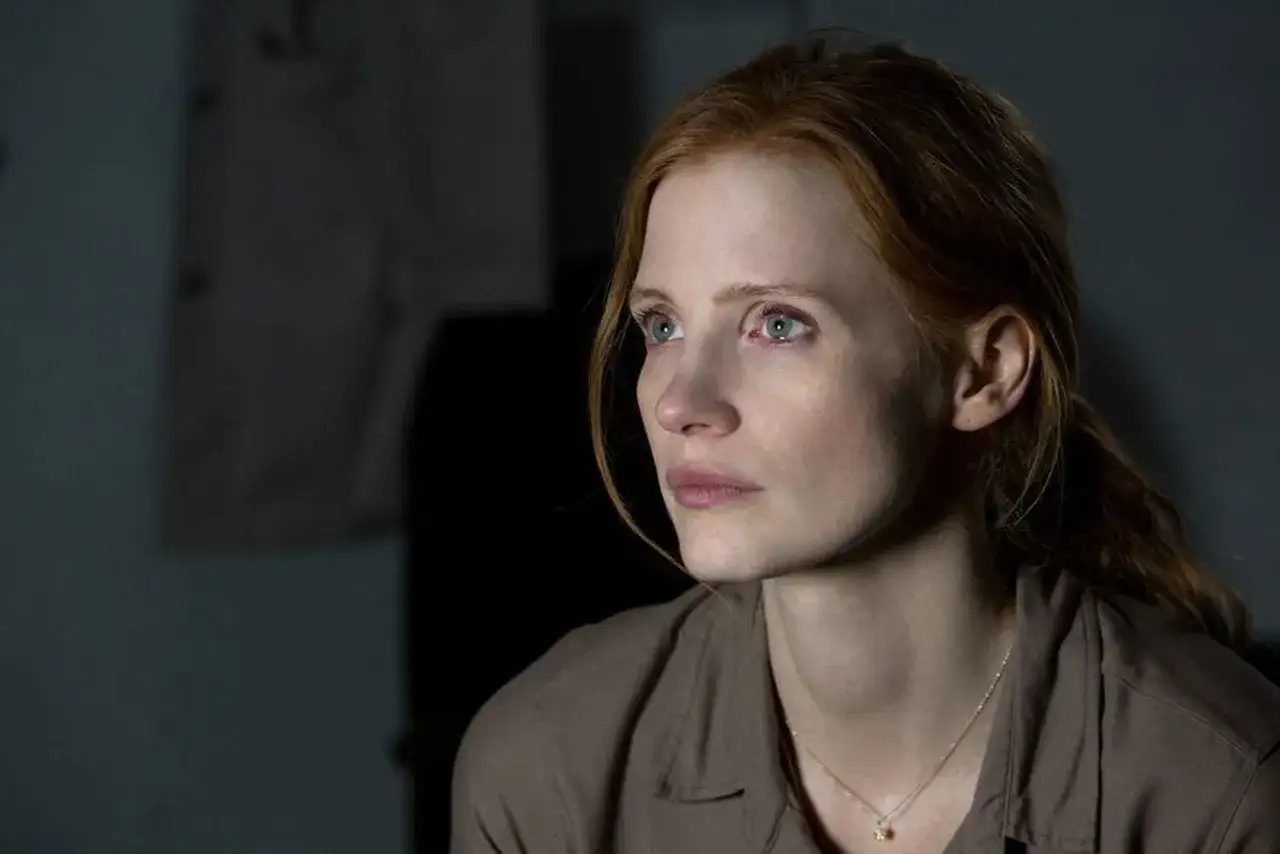 Primo piano di Jessica Chastain in un film, con sguardo intenso e capelli rossi raccolti.
