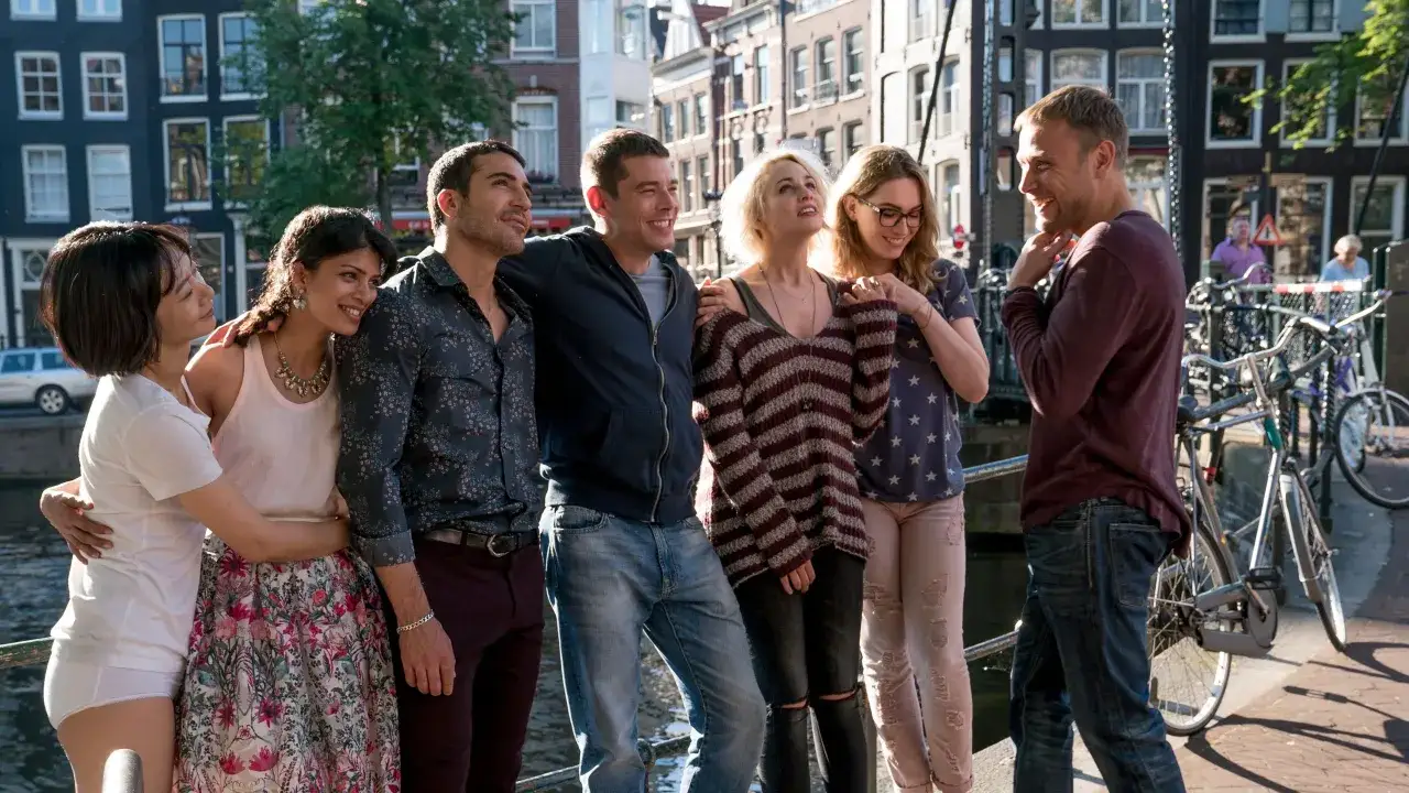 Il cast di Sense8 riunito ad Amsterdam, sorridenti e abbracciati lungo un canale, con biciclette sullo sfondo.