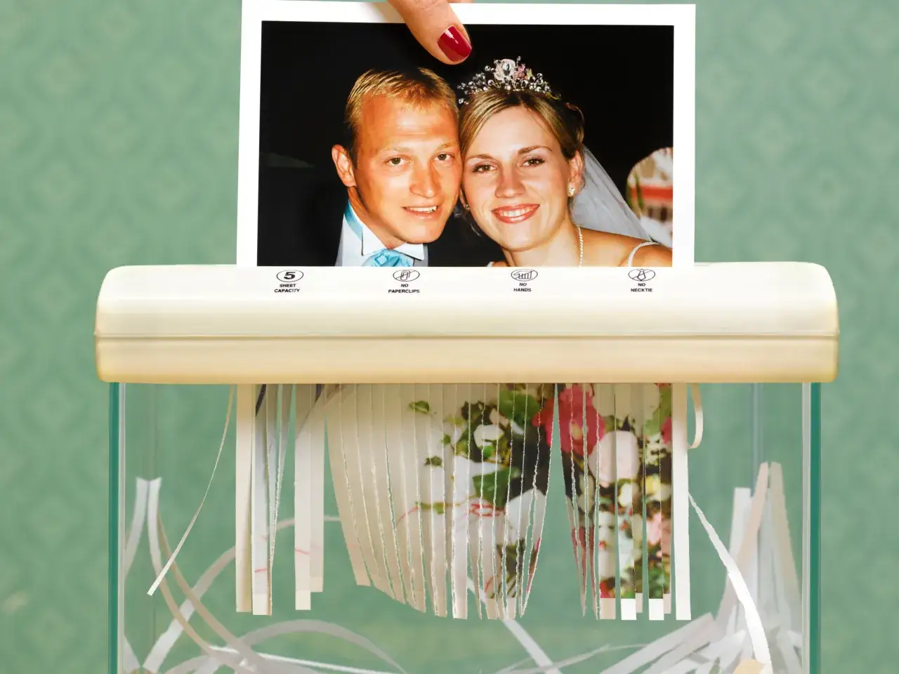 Una mano distrugge una foto di matrimonio, segnando la fine di una storia.