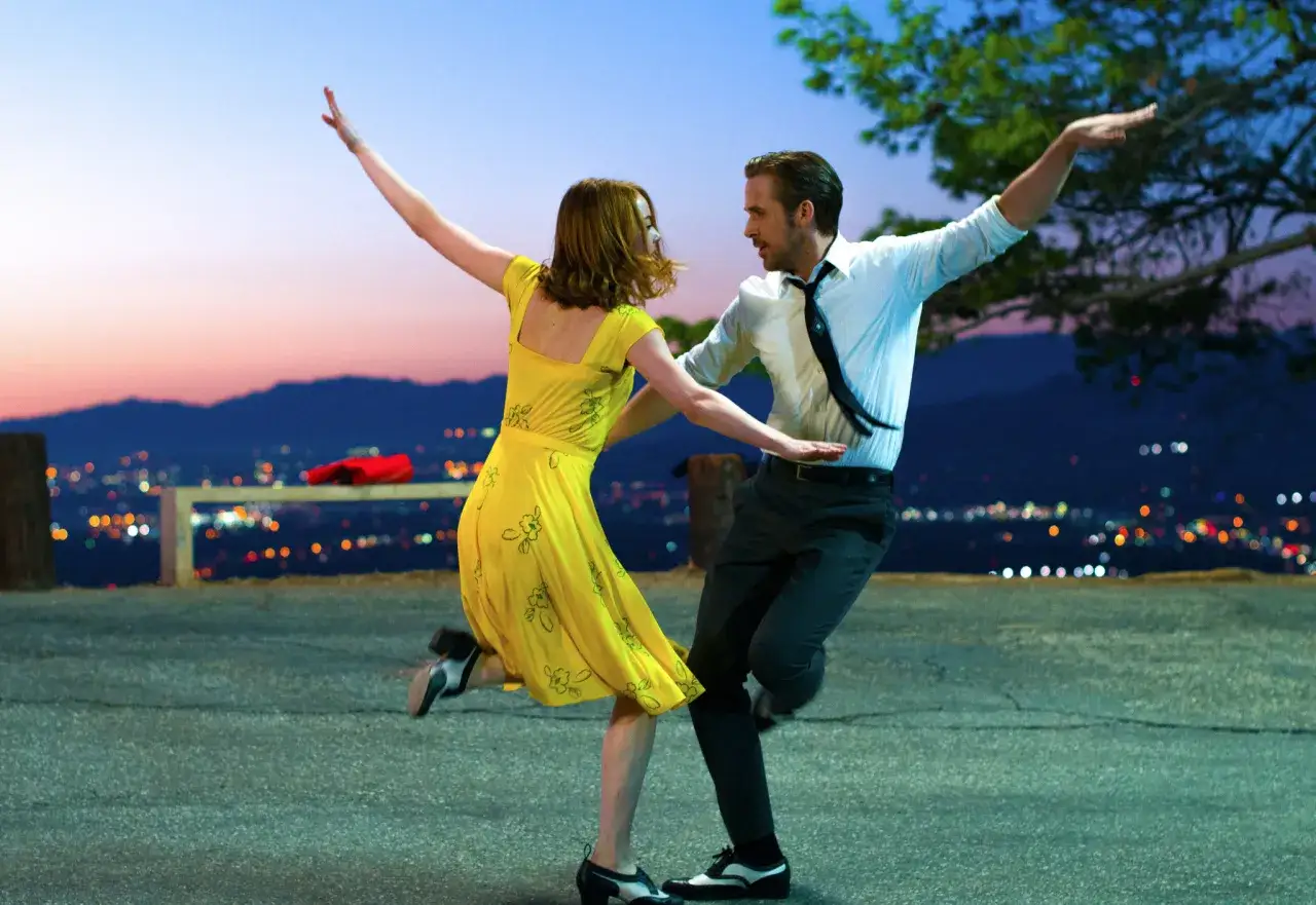 Il cast di La La Land balla al tramonto con la città illuminata sullo sfondo.
