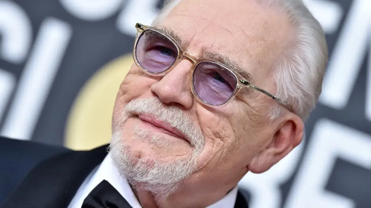 Brian Cox, con occhiali e barba bianca, un volto noto per i suoi film e programmi TV.