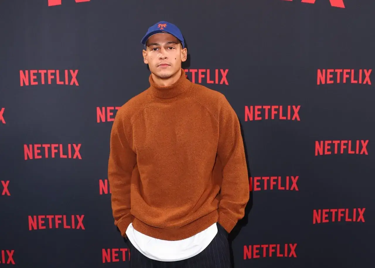 Giovane uomo con cappellino blu e maglione arancione, pronto per un film di 60 minuti.