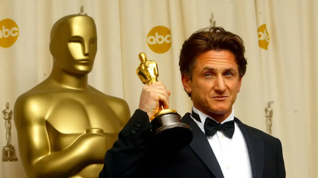 Sean Penn, vincitore dell'Oscar per Mystic River, posa con il suo premio accanto a un Oscar gigante.