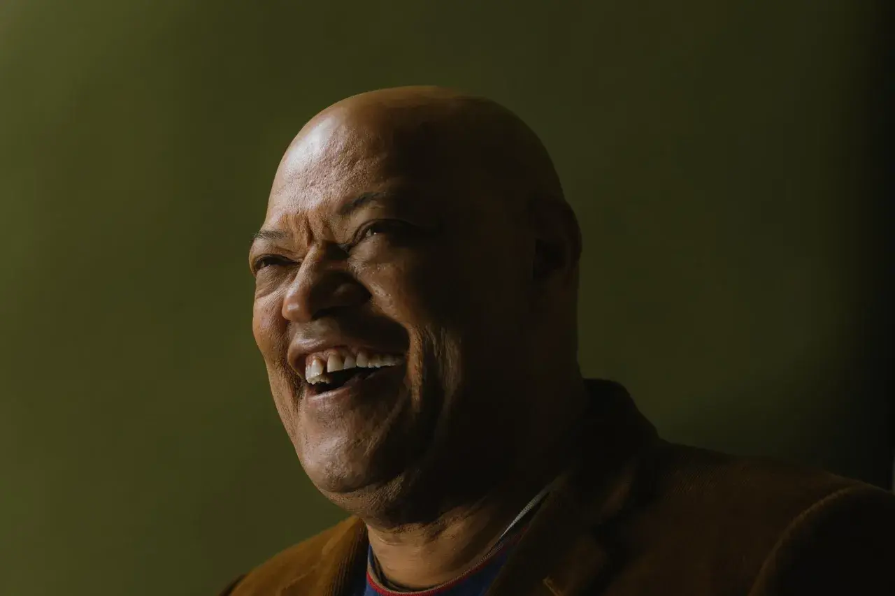 Laurence Fishburne ride con un sorriso contagioso, un'espressione che ricorda i suoi ruoli indimenticabili nei film.