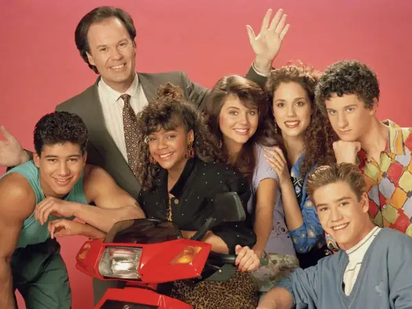 Cast del programma televisivo Bayside School posa sorridente con uno scooter rosso.