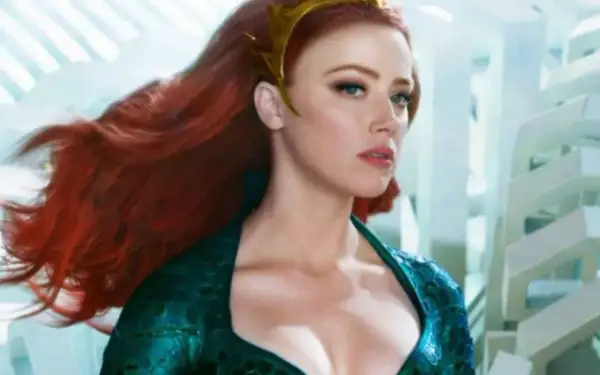 Amber Heard in un film, con lunghi capelli rossi e un diadema dorato, indossa un abito verde acqua.