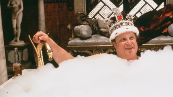 Un uomo con una corona scintillante, immerso in una vasca piena di schiuma, sorride. Sembra che sua maestà viene da Las Vegas, pronto per un bagno regale.