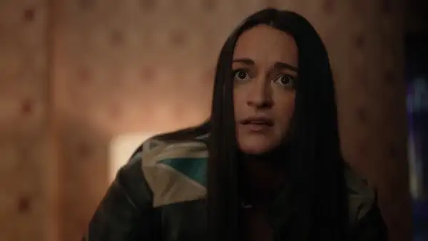 La protagonista di Resident Alien, con un'espressione sorpresa, indossa una giacca di pelle con dettagli colorati.