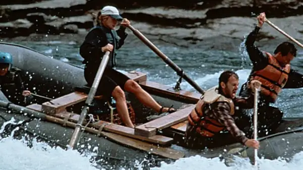Il cast di The River Wild affronta rapide impetuose su un gommone, remando con forza per sopravvivere.