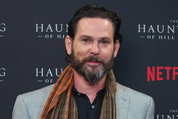 Henry Thomas, noto per i suoi film e programmi TV, sorride con una sciarpa colorata.