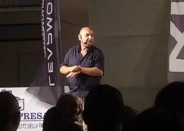 Giovanni Cacioppo, con un microfono all'orecchio, parla a un pubblico. La sua storia sulla malattia ispira.