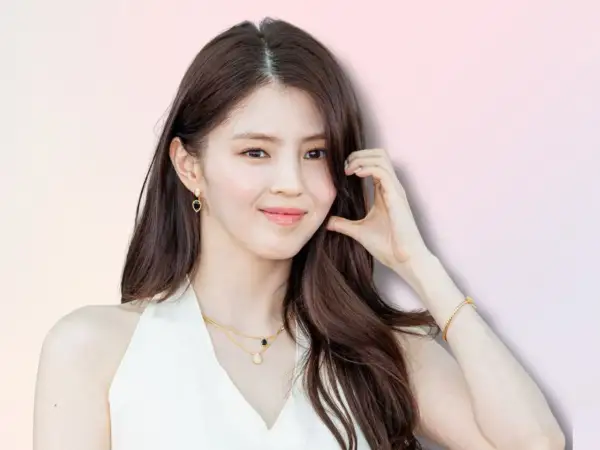 Han So Hee, con capelli castani lunghi, indossa orecchini a goccia e una collana d'oro.