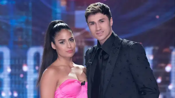 Mirko e Perla, un duo affascinante sul palco, lei con un abito rosa acceso, lui elegante in giacca nera tempestata di cristalli.