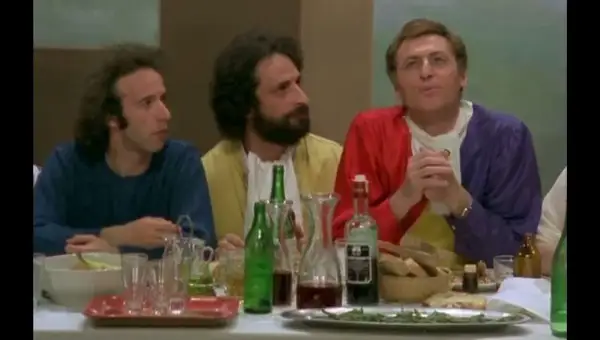 Il cast de "Il Pap'occhio" a tavola, tra bottiglie di vino e pane.