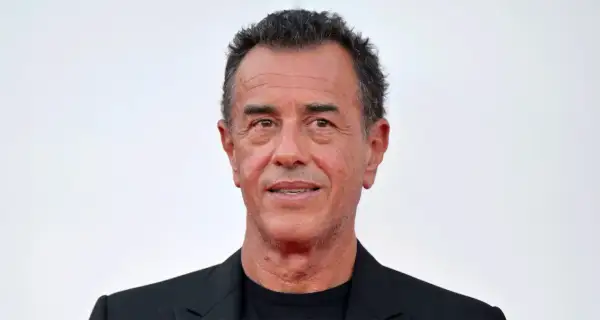 Matteo Garrone, regista italiano, con un sorriso enigmatico. La sua carriera è segnata da film potenti e visivamente sorprendenti.
